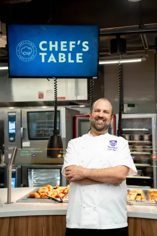 Chef standing Infront of chef's table sign