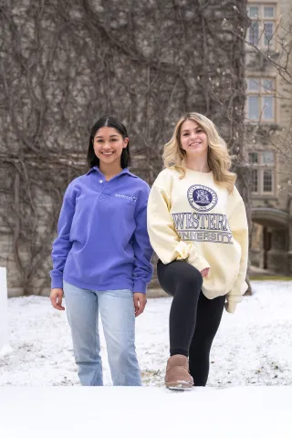 Two woman standing in snow posing for picture