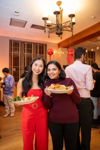 Two woman with plates of food posing for photo